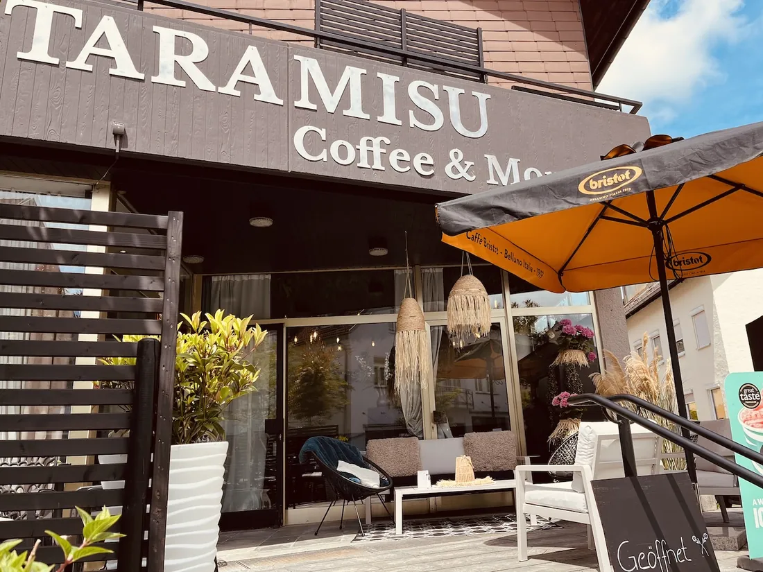 Das TaraMisu von außen: Schriftzug Coffee & More, Terrasse mit Sesseln und Sonnenschirm